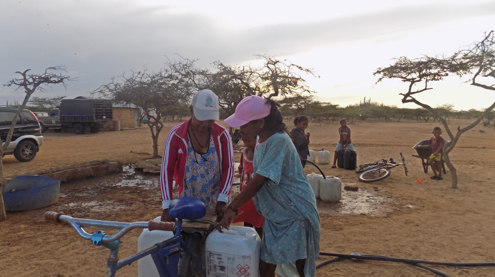 Llevar agua desde los pozos artesanales hasta sus casas no es tarea fácil. Menos para las mujeres, que se las ingenian para equilibrar pesadas vasijas en su bicicleta. Foto: María Teresa Arboleda Grajales.