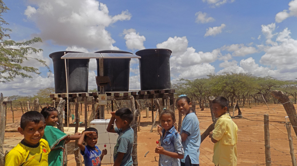 Estudiantes de la escuela Kasumana junto al panel solar y a los tanques de agua que abastecen a 17 rancherías. Foto: María Teresa Arboleda Grajales